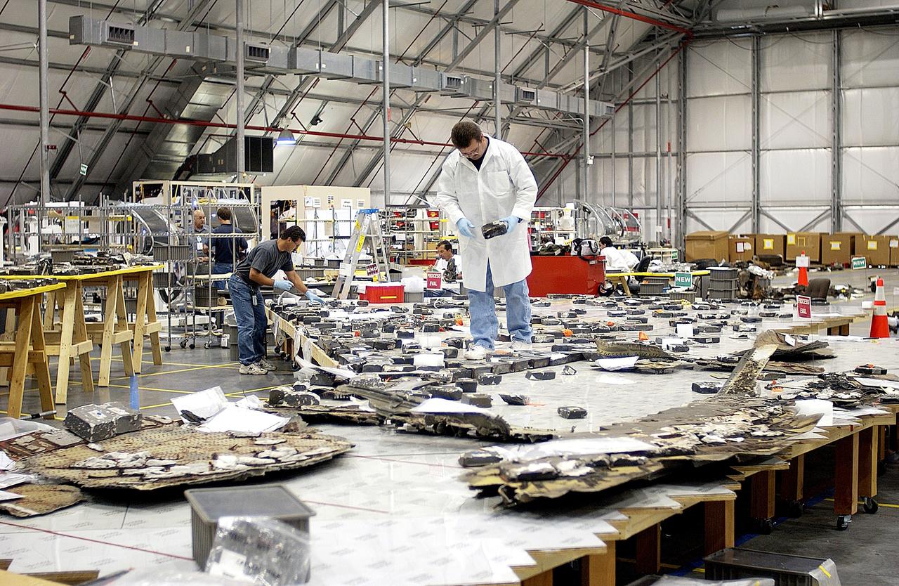 KENNEDY SPACE CENTER, FLA. -  Members of the Columbia Reconstruction Project Team place pieces of debris on a table in the RLV Hangar.   The items shipped to KSC number more than 82,000 and weigh 84,800 pounds or 38 percent of the total dry weight of Columbia.  Of those items, 78,760 have been identified, with 753 placed on the left wing grid in the Hangar.