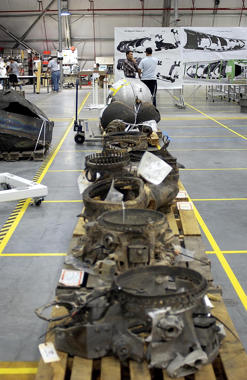 KENNEDY SPACE CENTER, FLA. - Large items of Columbia debris fill a long table in the RLV Hangar.  The items shipped to KSC number more than 82,000 and weigh 84,800 pounds or 38 percent of the total dry weight of Columbia.  Of those items, 78,760 have been identified, with 753 placed on the left wing grid in the Hangar.