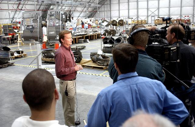 NASA image: KENNEDY SPACE CENTER, FLA. - Shuttle Launch Director Mike Leinbach talks to the media in the RLV Hangar, site of the collection of Columbia debris undergoing examination.  The items shipped to KSC number more than 82,000 and weigh 84,800 pounds or 38 percent of the total dry weight of Columbia.  Of those items, 78,760 have been identified, with 753 placed on the left wing grid in the Hangar.