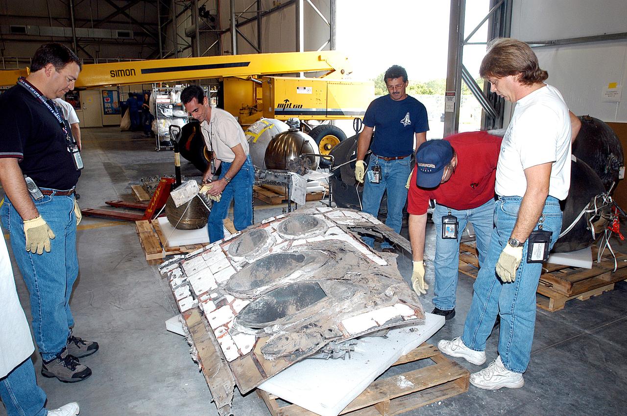 KENNEDY SPACE CENTER, FLA. -  Members of the Columbia Reconstruction Project Team work with pieces of debris in the RLV Hangar. The items shipped to KSC number more than 82,000 and weigh 84,800 pounds or 38 percent of the total dry weight of Columbia. Of those items, 78,760 have been identified, with 753 placed on the left wing grid in the Hangar.