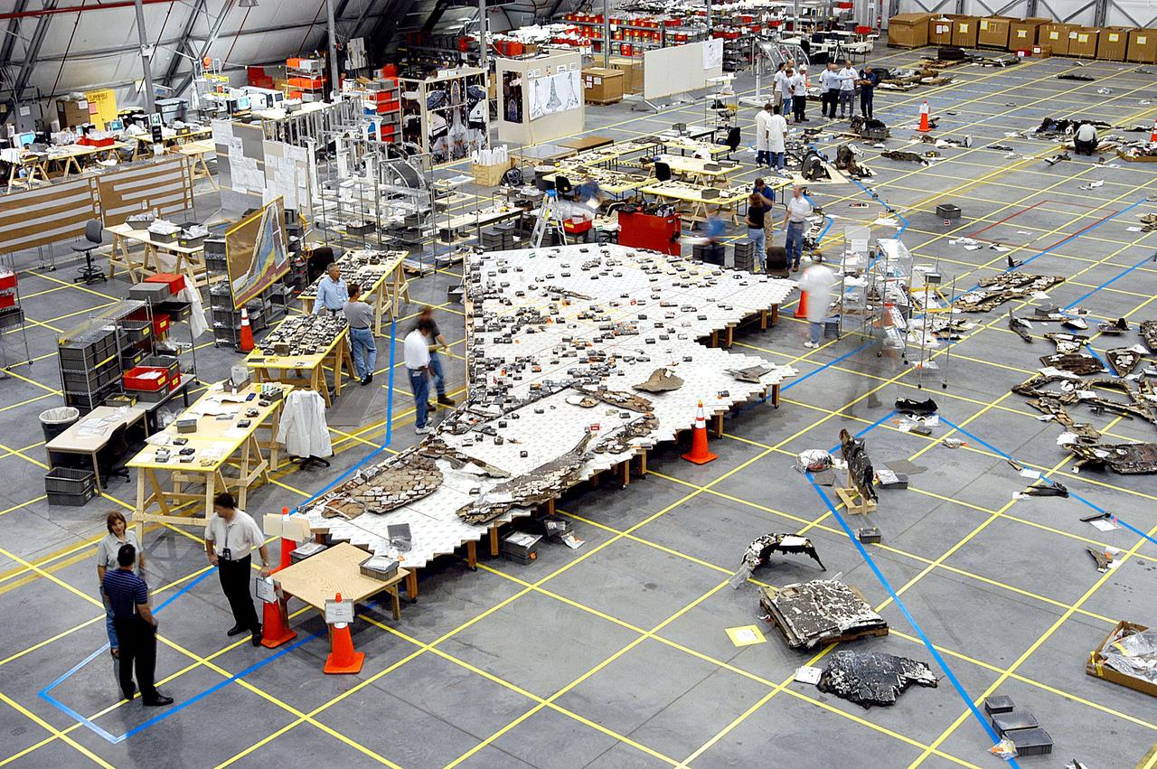 KENNEDY SPACE CENTER, FLA. -  In the RLV hangar, members of the Columbia Reconstruction Team work to identify pieces of Thermal Protection System tile from the left wing of Columbia recovered during the search and recovery efforts in East Texas.  The items shipped to KSC number more than 82,000 and weigh 84,800 pounds or 38 percent of the total dry weight of Columbia. Of those items, 78,760 have been identified, with 753 placed on the left wing grid in the Hangar.