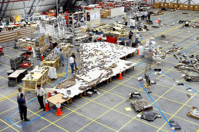 NASA image: KENNEDY SPACE CENTER, FLA. -  In the RLV hangar, members of the Columbia Reconstruction Team work to identify pieces of Thermal Protection System tile from the left wing of Columbia recovered during the search and recovery efforts in East Texas.  The items shipped to KSC number more than 82,000 and weigh 84,800 pounds or 38 percent of the total dry weight of Columbia. Of those items, 78,760 have been identified, with 753 placed on the left wing grid in the Hangar.