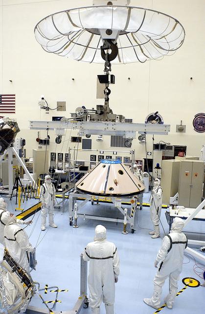 NASA image: KENNEDY SPACE CENTER, FLA. -  Workers in the Payload Hazardous Servicing Facility prepare to lift and move the backshell that will cover the Mars Exploration Rover 1 (MER-1) and its lander.  NASA's twin Mars Exploration Rovers are designed to study the history of water on Mars. These robotic geologists are equipped with a robotic arm, a drilling tool, three spectrometers, and four pairs of cameras that allow them to have a human-like, 3D view of the terrain. Each rover could travel as far as 100 meters in one day to act as Mars scientists' eyes and hands, exploring an environment where humans can't yet go.  MER-1 is scheduled to launch June 25 as MER-B aboard a Delta II rocket from Cape Canaveral Air Force Station.
