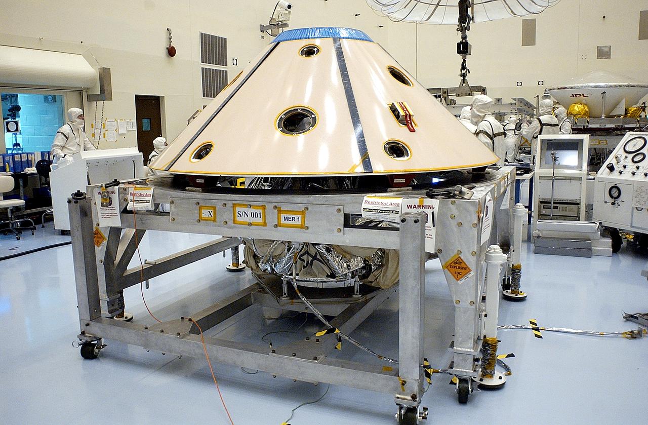 KENNEDY SPACE CENTER, FLA. - The backshell is in place over the Mars Exploration Rover 1 (MER-1).  The backshell is a protective cover for the rover.  NASA's twin Mars Exploration Rovers are designed to study the history of water on Mars. These robotic geologists are equipped with a robotic arm, a drilling tool, three spectrometers, and four pairs of cameras that allow them to have a human-like, 3D view of the terrain. Each rover could travel as far as 100 meters in one day to act as Mars scientists' eyes and hands, exploring an environment where humans can't yet go.  MER-1 is scheduled to launch June 25 as MER-B aboard a Delta II rocket from Cape Canaveral Air Force Station.