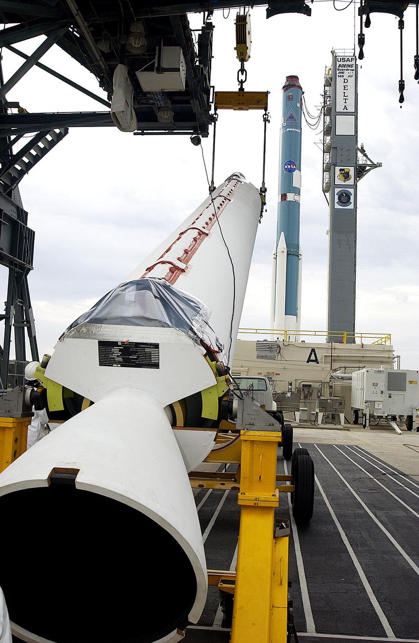 KENNEDY SPACE CENTER, FLA. - On Launch Complex 17-A, Cape Canaveral Air Force Station, a solid rocket booster is raised off the transporter.  When vertical, it will be lifted up the launch tower and mated to the Delta rocket (in the background) to launch Mars Exploration Rover 2. NASA’s twin Mars Exploration Rovers are designed to study the history of water on Mars. These robotic geologists are equipped with a robotic arm, a drilling tool, three spectrometers, and four pairs of cameras that allow them to have a human-like, 3D view of the terrain. Each rover could travel as far as 100 meters in one day to act as Mars scientists' eyes and hands, exploring an environment where humans can’t yet go.  MER-2 is scheduled to launch June 5 as MER-A.  MER-1 (MER-B) will launch June 25.