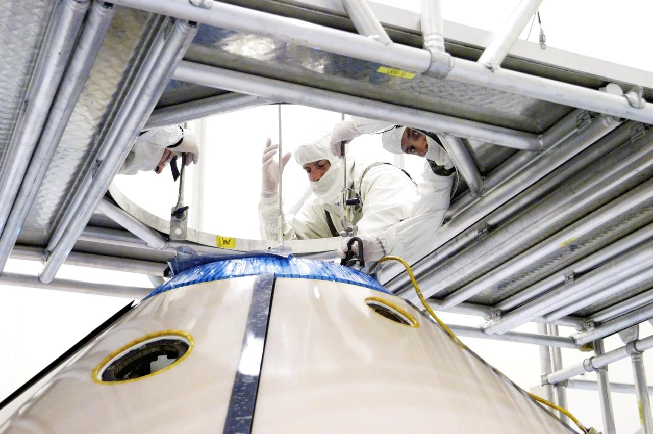 KENNEDY SPACE CENTER, FLA. -  Workers attach an overhead crane to the Mars Exploration Rover 1 (MER-1) inside the upper backshell.   The backshell will be moved and attached to the lower heat shield.  NASA's twin Mars Exploration Rovers are designed to study the history of water on Mars. These robotic geologists are equipped with a robotic arm, a drilling tool, three spectrometers, and four pairs of cameras that allow them to have a human-like, 3D view of the terrain. Each rover could travel as far as 100 meters in one day to act as Mars scientists' eyes and hands, exploring an environment where humans can't yet go.  MER-1 is scheduled to launch June 25 as MER-B aboard a Delta II rocket from Cape Canaveral Air Force Station.