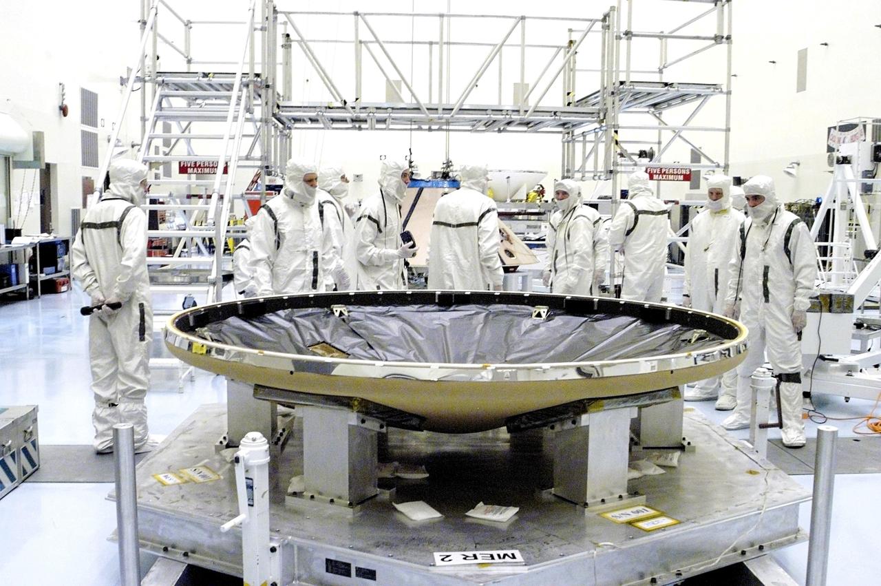 KENNEDY SPACE CENTER, FLA. - In the Payload Hazardous Servicing Facility, the heat shield (foreground) is ready to be mated with the upper backshell/ Mars Exploration Rover 1 (MER-1), in the background.  NASA's twin Mars Exploration Rovers are designed to study the history of water on Mars. These robotic geologists are equipped with a robotic arm, a drilling tool, three spectrometers, and four pairs of cameras that allow them to have a human-like, 3D view of the terrain. Each rover could travel as far as 100 meters in one day to act as Mars scientists' eyes and hands, exploring an environment where humans can't yet go.  MER-1 is scheduled to launch June 25 as MER-B aboard a Delta II rocket from Cape Canaveral Air Force Station.
