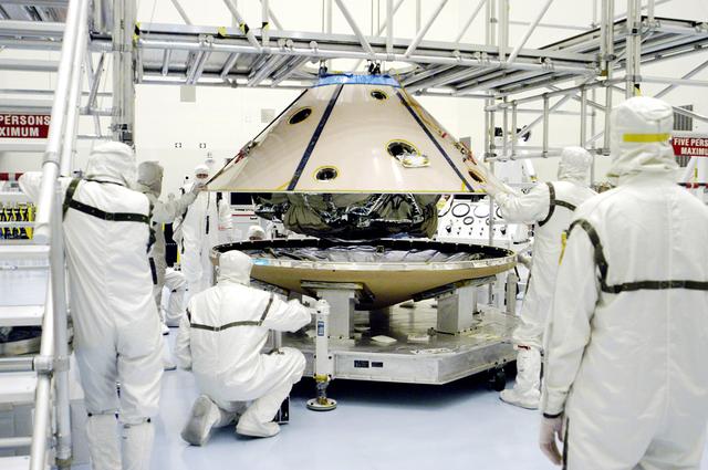 NASA image: KENNEDY SPACE CENTER, FLA. - In the Payload Hazardous Servicing Facility, workers lower the backshell with the Mars Exploration Rover 1 (MER-1) onto the heat shield.  The two components form the aeroshell that will protect the rover on its journey to Mars.  NASA's twin Mars Exploration Rovers are designed to study the history of water on Mars. These robotic geologists are equipped with a robotic arm, a drilling tool, three spectrometers, and four pairs of cameras that allow them to have a human-like, 3D view of the terrain. Each rover could travel as far as 100 meters in one day to act as Mars scientists' eyes and hands, exploring an environment where humans can't yet go.  MER-1 is scheduled to launch June 25 as MER-B aboard a Delta II rocket from Cape Canaveral Air Force Station.