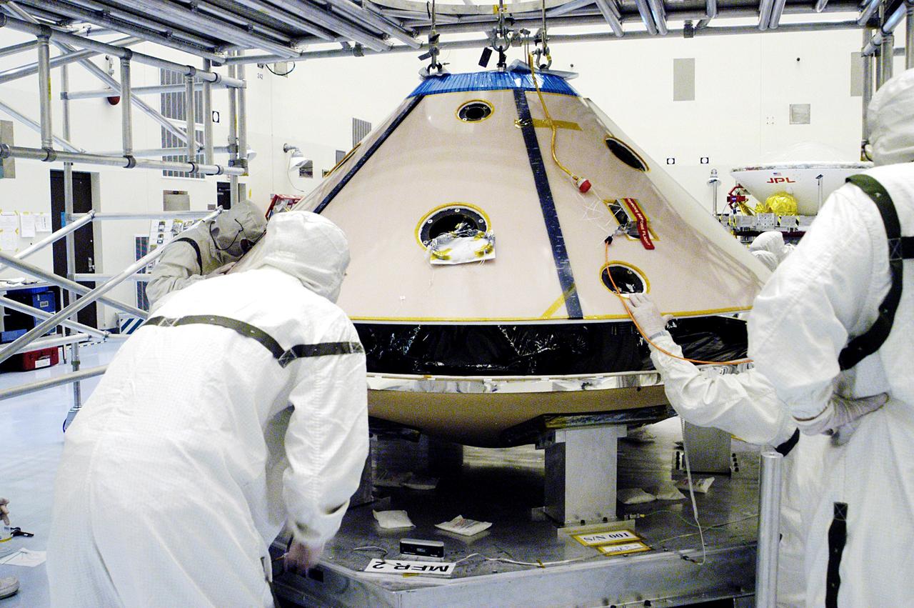 KENNEDY SPACE CENTER, FLA. - In the Payload Hazardous Servicing Facility, workers lower the backshell with the Mars Exploration Rover 1 (MER-1) onto the heat shield.  The two components form the aeroshell that will protect the rover on its journey to Mars.  NASA's twin Mars Exploration Rovers are designed to study the history of water on Mars. These robotic geologists are equipped with a robotic arm, a drilling tool, three spectrometers, and four pairs of cameras that allow them to have a human-like, 3D view of the terrain. Each rover could travel as far as 100 meters in one day to act as Mars scientists' eyes and hands, exploring an environment where humans can't yet go.  MER-1 is scheduled to launch June 25 as MER-B aboard a Delta II rocket from Cape Canaveral Air Force Station.