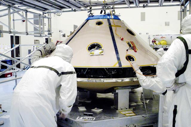NASA image: KENNEDY SPACE CENTER, FLA. - In the Payload Hazardous Servicing Facility, workers lower the backshell with the Mars Exploration Rover 1 (MER-1) onto the heat shield.  The two components form the aeroshell that will protect the rover on its journey to Mars.  NASA's twin Mars Exploration Rovers are designed to study the history of water on Mars. These robotic geologists are equipped with a robotic arm, a drilling tool, three spectrometers, and four pairs of cameras that allow them to have a human-like, 3D view of the terrain. Each rover could travel as far as 100 meters in one day to act as Mars scientists' eyes and hands, exploring an environment where humans can't yet go.  MER-1 is scheduled to launch June 25 as MER-B aboard a Delta II rocket from Cape Canaveral Air Force Station.
