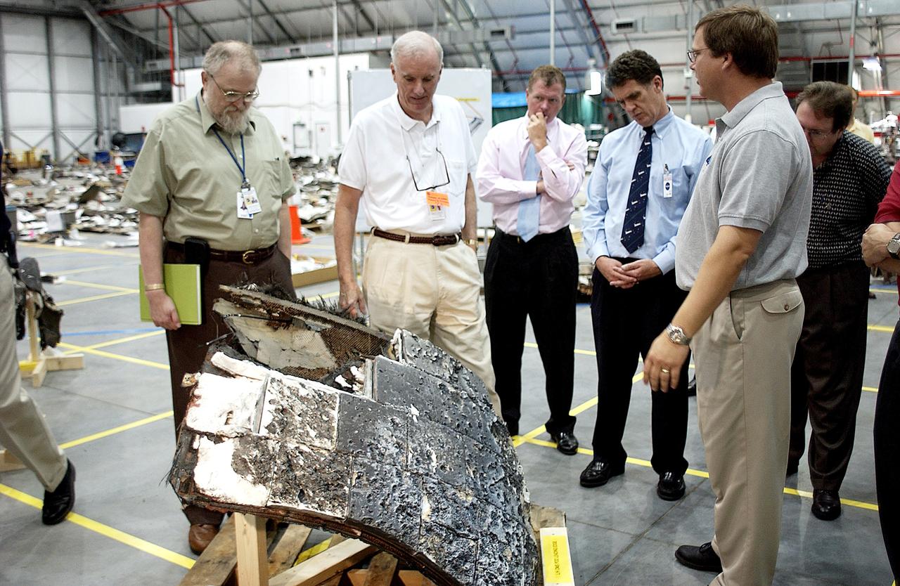 KENNEDY SPACE CENTER, FLA. - Adm. Harold Gehman, center, chairman of the Columbia Investigation Accident Board,  looks at a large piece of Columbia debris in the RLV Hangar.  He and other board members are visiting the Hangar as part of the ongoing investigation.  To the right of Gehman are U.S. Representatives Tom Feeney and Dave Weldon.  Recovery efforts as of May 5 included 82,500 pieces of debris weighing 84,800 pounds, almost 40 percent of the total dry weight of the shuttle.  About 25,000 personnel took part, utilizing almost 1.5 million total man-hours in the recovery effort and involving more than 130 federal, state and local agencies.  The operation was also supported by more than 270 organizations that included businesses and volunteer groups.
