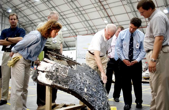 NASA image: KENNEDY SPACE CENTER, FLA. - In the RLV Hangar, Adm. Harold Gehman, center, chairman of the Columbia Investigation Accident Board, gestures toward a large piece of Columbia debris.  He and other board members are visiting the Hangar as part of the ongoing investigation.  At right is U.S. Representative Dave Weldon; behind him is U.S. Representative Tom Feeney.  Recovery efforts as of May 5 included 82,500 pieces of debris weighing 84,800 pounds, almost 40 percent of the total dry weight of the shuttle.  About 25,000 personnel took part, utilizing almost 1.5 million total man-hours in the recovery effort and involving more than 130 federal, state and local agencies.  The operation was also supported by more than 270 organizations that included businesses and volunteer groups.