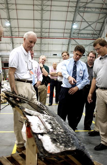 NASA image: KENNEDY SPACE CENTER, FLA. - In the RLV Hangar, Adm. Harold Gehman, center, chairman of the Columbia Investigation Accident Board, looks on while U.S. Representative Dave Weldon (second from right) points at a piece of Columbia debris.  Behind Gehman is U.S. Representative Tom Feeney.  Gehman and other board members are visiting KSC as part of the ongoing investigation.  Recovery efforts as of May 5 included 82,500 pieces of debris weighing 84,800 pounds, almost 40 percent of the total dry weight of the shuttle.  About 25,000 personnel took part, utilizing almost 1.5 million total man-hours in the recovery effort and involving more than 130 federal, state and local agencies.  The operation was also supported by more than 270 organizations that included businesses and volunteer groups.