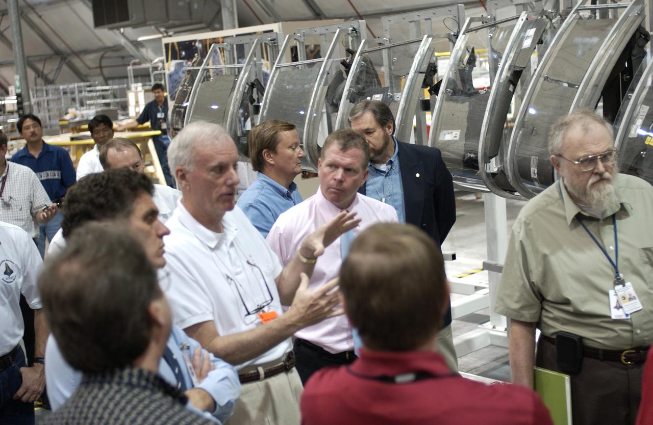 In the RLV Hangar, Adm. Harold Gehman (gesturing) and the Columbia Investigation Accident Board are visiting KSC as part of the ongoing investigation.  Flanking Gehman are U. S. Representatives Dave Weldon (left) and Tom Feeney (right), who accompanied the board.  Recovery efforts as of May 5 included 82,500 pieces of debris weighing 84,800 pounds, almost 40 percent of the total dry weight of the shuttle.  About 25,000 personnel took part, utilizing almost 1.5 million total man-hours in the recovery effort and involving more than 130 federal, state and local agencies.  The operation was also supported by more than 270 organizations that included businesses and volunteer groups.