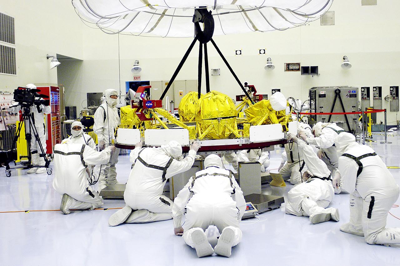 KENNEDY SPACE CENTER, FLA. - In the Payload Hazardous Servicing Facility, workers help guide the cruise stage of Mars Exploration Rover 1 (MER-1) as it is lowered onto blocks.  The cruise stage will be integrated with the aeroshell, the entry vehicle.   NASA’s twin Mars Exploration Rovers are designed to study the history of water on Mars. These robotic geologists are equipped with a robotic arm, a drilling tool, three spectrometers, and four pairs of cameras that allow them to have a human-like, 3D view of the terrain. Each rover could travel as far as 100 meters in one day to act as Mars scientists' eyes and hands, exploring an environment where humans can’t yet go.  The MER-1 is scheduled to launch June 25 from Launch Pad 17-A, Cape Canaveral Air Force Station.