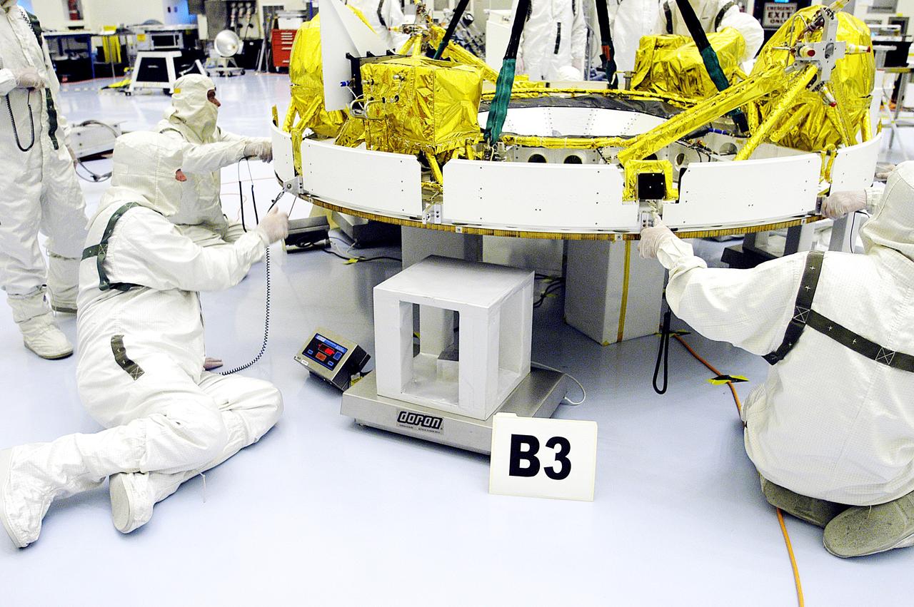 KENNEDY SPACE CENTER, FLA. - In the Payload Hazardous Servicing Facility, workers help guide the cruise stage of Mars Exploration Rover 1 (MER-1) as it is lowered onto blocks.  The cruise stage will be integrated with the aeroshell, the entry vehicle.   NASA’s twin Mars Exploration Rovers are designed to study the history of water on Mars. These robotic geologists are equipped with a robotic arm, a drilling tool, three spectrometers, and four pairs of cameras that allow them to have a human-like, 3D view of the terrain. Each rover could travel as far as 100 meters in one day to act as Mars scientists' eyes and hands, exploring an environment where humans can’t yet go.  The MER-1 is scheduled to launch June 25 from Launch Pad 17-A, Cape Canaveral Air Force Station.