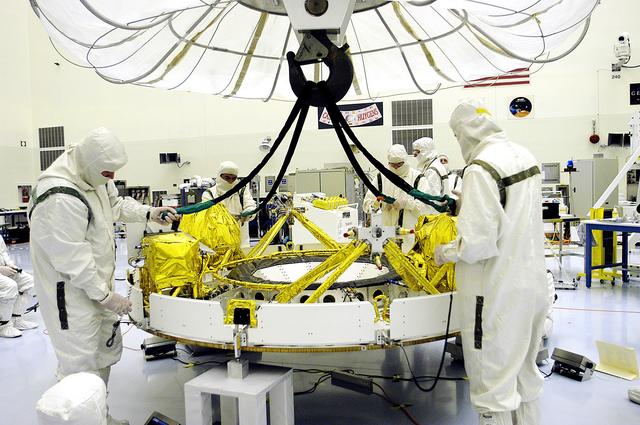 NASA image: KENNEDY SPACE CENTER, FLA. - In the Payload Hazardous Servicing Facility, workers reattach the tethers of the overhead crane that lowered the cruise stage of Mars Exploration Rover 1 (MER-1) onto blocks.  The cruise stage will be lifted and integrated with the aeroshell, the entry vehicle.   NASA’s twin Mars Exploration Rovers are designed to study the history of water on Mars. These robotic geologists are equipped with a robotic arm, a drilling tool, three spectrometers, and four pairs of cameras that allow them to have a human-like, 3D view of the terrain. Each rover could travel as far as 100 meters in one day to act as Mars scientists' eyes and hands, exploring an environment where humans can’t yet go.  The MER-1 is scheduled to launch June 25 from Launch Pad 17-A, Cape Canaveral Air Force Station.