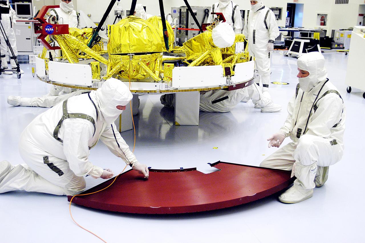 KENNEDY SPACE CENTER, FLA. - In the Payload Hazardous Servicing Facility, workers check one of the cruise stage solar panel protective covers on Mars Exploration Rover 1 (MER-1).  The cruise stage will be integrated with the aeroshell, the entry vehicle.   NASA’s twin Mars Exploration Rovers are designed to study the history of water on Mars. These robotic geologists are equipped with a robotic arm, a drilling tool, three spectrometers, and four pairs of cameras that allow them to have a human-like, 3D view of the terrain. Each rover could travel as far as 100 meters in one day to act as Mars scientists' eyes and hands, exploring an environment where humans can’t yet go.  The MER-1 is scheduled to launch June 25 from Launch Pad 17-A, Cape Canaveral Air Force Station.