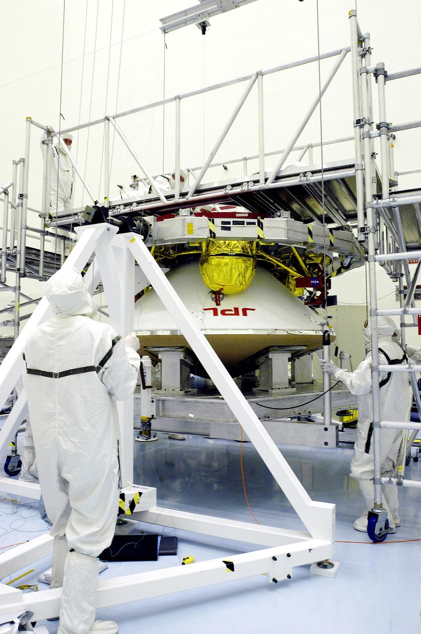 KENNEDY SPACE CENTER, FLA. - Workers in the Payload Hazardous Servicing Facility check the mating of the Mars Exploration Rover 1 (MER-1) cruise stage to the lander below it.  NASA's twin Mars Exploration Rovers are designed to study the history of water on Mars. These robotic geologists are equipped with a robotic arm, a drilling tool, three spectrometers, and four pairs of cameras that allow them to have a human-like, 3D view of the terrain. Each rover could travel as far as 100 meters in one day to act as Mars scientists' eyes and hands, exploring an environment where humans can't yet go.  MER-1 is scheduled to launch June 25 as MER-B aboard a Delta II rocket from Cape Canaveral Air Force Station.