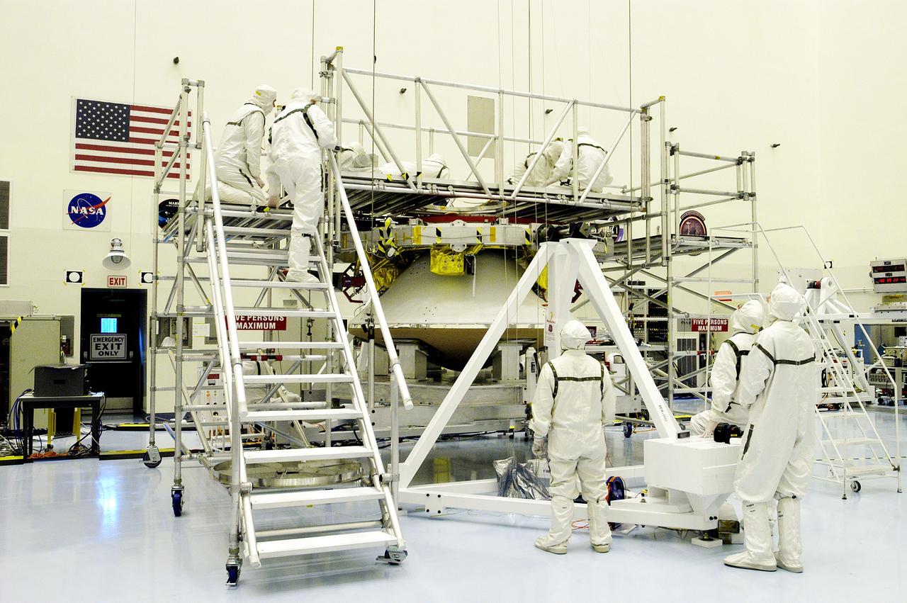 KENNEDY SPACE CENTER, FLA. - Workers in the Payload Hazardous Servicing Facility check the mating of the Mars Exploration Rover 1 (MER-1) cruise stage to the lander below it.  NASA's twin Mars Exploration Rovers are designed to study the history of water on Mars. These robotic geologists are equipped with a robotic arm, a drilling tool, three spectrometers, and four pairs of cameras that allow them to have a human-like, 3D view of the terrain. Each rover could travel as far as 100 meters in one day to act as Mars scientists' eyes and hands, exploring an environment where humans can't yet go.  MER-1 is scheduled to launch June 25 as MER-B aboard a Delta II rocket from Cape Canaveral Air Force Station.