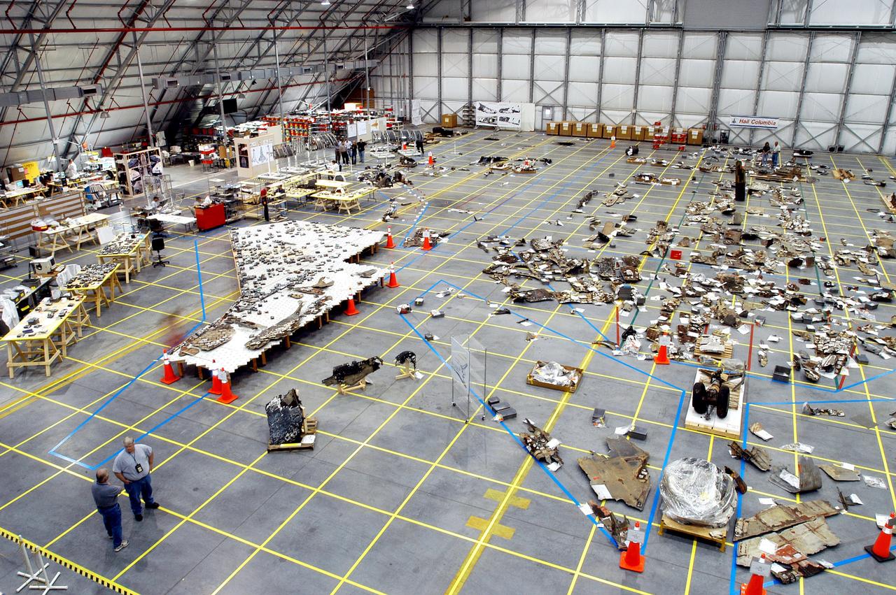 KENNEDY SPACE CENTER, FLA. - An overview of the Columbia debris hangar shows the orbiter outline on the floor with some of the 78,760 pieces identified to date, as well as tables on the left that hold tiles.  More than 82,500 pieces of shuttle debris have been rcovered.