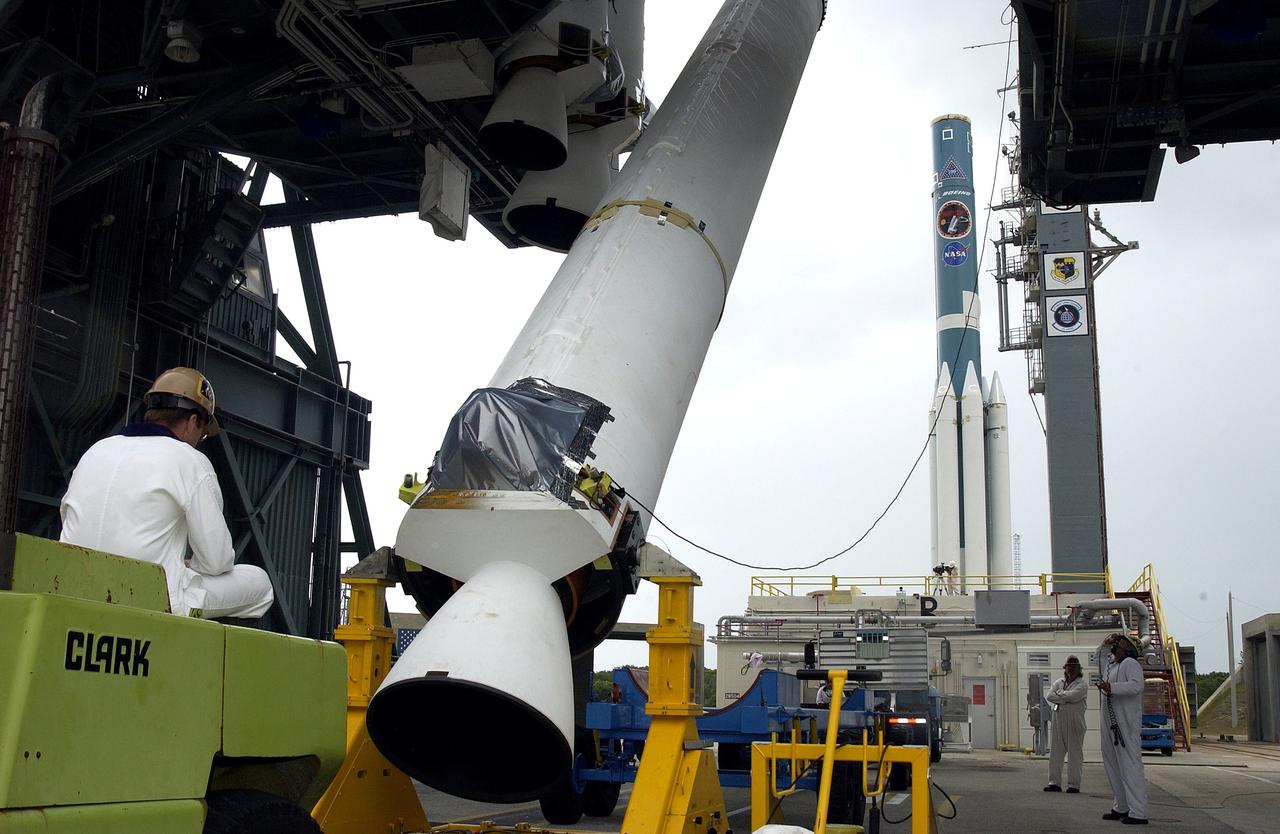 KENNEDY SPACE CENTER, FLA. -  On Launch Complex 17-B, Cape Canaveral Air Force Station, a solid rocket booster is lifted to vertical.  It will be mated to the Delta II rocket (in the background) for the Mars Exploration Rover 1 (MER-1) launch June 25.  NASA’s twin Mars Exploration Rovers are designed to study the history of water on Mars. These robotic geologists are equipped with a robotic arm, a drilling tool, three spectrometers, and four pairs of cameras that allow them to have a human-like, 3D view of the terrain. Each rover could travel as far as 100 meters in one day to act as Mars scientists' eyes and hands, exploring an environment where humans can’t yet go.  MER-2 (MER-A) will launch June 5.