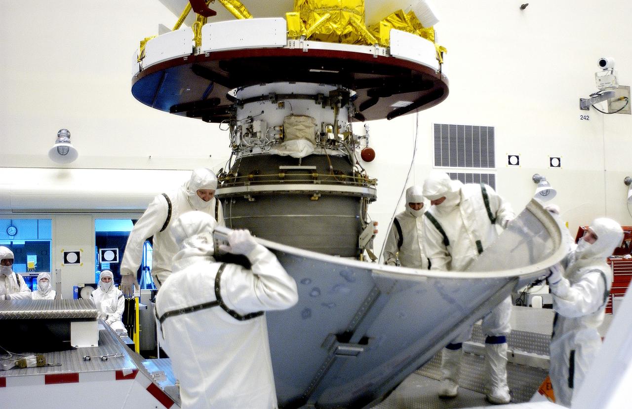 KENNEDY SPACE CENTER, FLA. -  Workers in the Payload Hazardous Servicing Facility place the lower sections of the transport canister around the Mars Exploration Rover 2 (MER-2).  After encapsulation, it will be transferred to Launch Complex 17-A, Cape Canaveral Air Force Station.  MER-2 is one of NASA's twin Mars Exploration Rovers designed to study the history of water on Mars. These robotic geologists are equipped with a robotic arm, a drilling tool, three spectrometers, and four pairs of cameras that allow them to have a human-like, 3D view of the terrain. Each rover could travel as far as 100 meters in one day to act as Mars scientists' eyes and hands, exploring an environment where humans can't yet go.  MER-2 is scheduled to launch no earlier than June 8 as MER-A aboard a Delta II rocket.