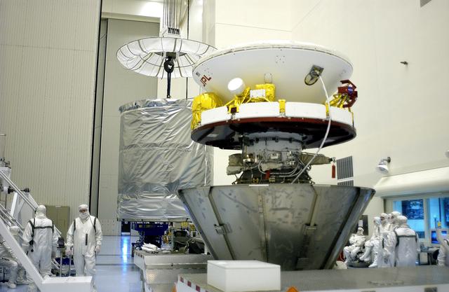 NASA image: KENNEDY SPACE CENTER, FLA. - In the Payload Hazardous Servicing Facility, an overhead crane (background) begins to lift the canister that will complete encapsulation of the Mars Exploration Rover 2 (MER-2) in the foreground.  After encapsulation, MER-2 will be transferred to Launch Complex 17-A, Cape Canaveral Air Force Station.  MER-2 is one of NASA's twin Mars Exploration Rovers designed to study the history of water on Mars. These robotic geologists are equipped with a robotic arm, a drilling tool, three spectrometers, and four pairs of cameras that allow them to have a human-like, 3D view of the terrain. Each rover could travel as far as 100 meters in one day to act as Mars scientists' eyes and hands, exploring an environment where humans can't yet go.  MER-2 is scheduled to launch no earlier than June 8 as MER-A aboard a Delta II rocket.