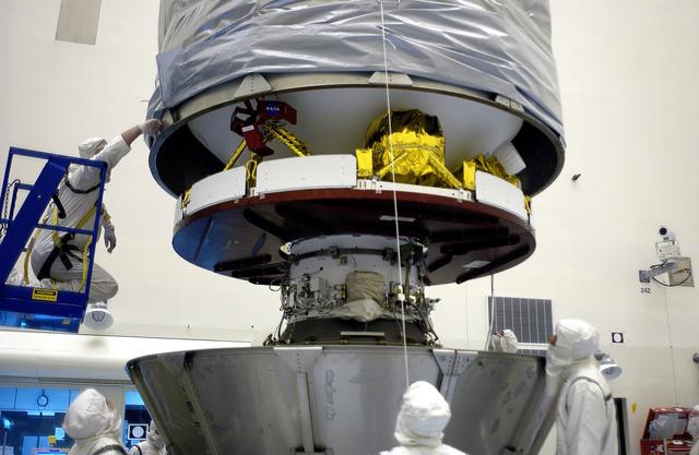 NASA image: KENNEDY SPACE CENTER, FLA. - In the Payload Hazardous Servicing Facility, an overhead crane lowers the canister that will complete encapsulation of the Mars Exploration Rover 2 (MER-2), at right.  After encapsulation, MER-2 will be transferred to Launch Complex 17-A, Cape Canaveral Air Force Station.  MER-2 is one of NASA's twin Mars Exploration Rovers designed to study the history of water on Mars. These robotic geologists are equipped with a robotic arm, a drilling tool, three spectrometers, and four pairs of cameras that allow them to have a human-like, 3D view of the terrain. Each rover could travel as far as 100 meters in one day to act as Mars scientists' eyes and hands, exploring an environment where humans can't yet go.  MER-2 is scheduled to launch no earlier than June 8 as MER-A aboard a Delta II rocket.