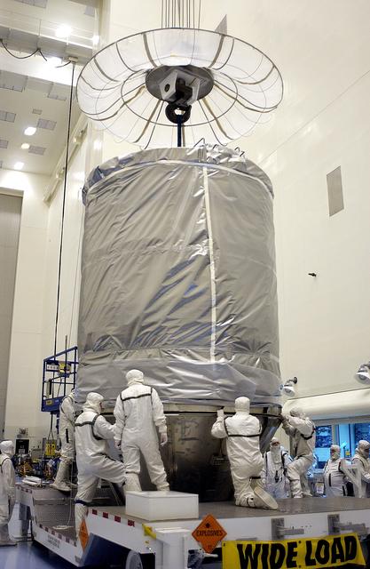 NASA image: KENNEDY SPACE CENTER, FLA. - In the Payload Hazardous Servicing Facility, an overhead crane lowers the canister that will complete encapsulation of the Mars Exploration Rover 2 (MER-2), at right.  After encapsulation, MER-2 will be transferred to Launch Complex 17-A, Cape Canaveral Air Force Station.  MER-2 is one of NASA's twin Mars Exploration Rovers designed to study the history of water on Mars. These robotic geologists are equipped with a robotic arm, a drilling tool, three spectrometers, and four pairs of cameras that allow them to have a human-like, 3D view of the terrain. Each rover could travel as far as 100 meters in one day to act as Mars scientists' eyes and hands, exploring an environment where humans can't yet go.  MER-2 is scheduled to launch no earlier than June 8 as MER-A aboard a Delta II rocket.