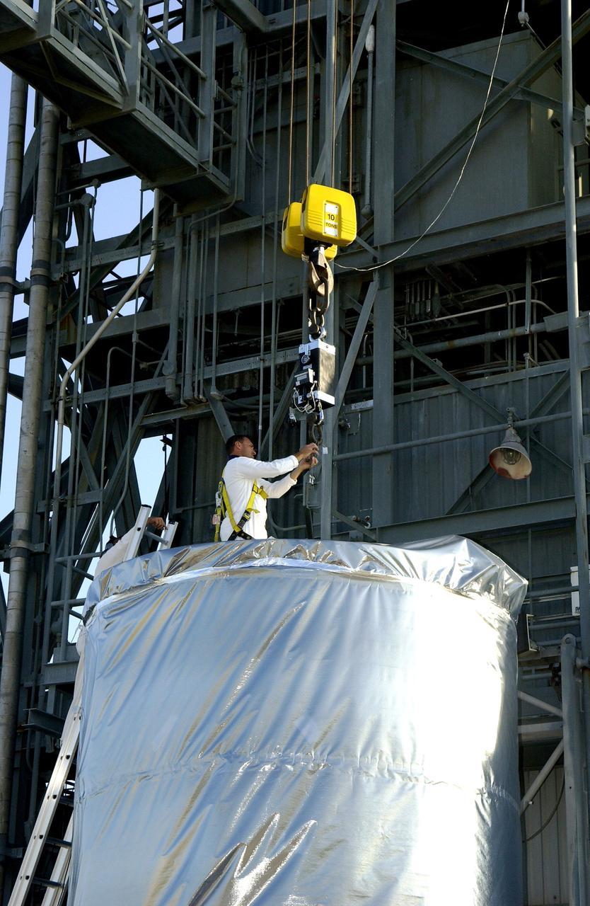 KENNEDY SPACE CENTER, FLA. - A  worker on Launch Pad 17-A, Cape Canaveral Air Force Station,  gets ready to attach a cable to the Mars Exploration Rover 2 (MER-2), inside the transport canister.  After it is lifted into the launch tower, it will be mated to the Delta II rocket for launch.  MER-2 is one of NASA's twin Mars Exploration Rovers designed to study the history of water on Mars. These robotic geologists are equipped with a robotic arm, a drilling tool, three spectrometers, and four pairs of cameras that allow them to have a human-like, 3D view of the terrain. Each rover could travel as far as 100 meters in one day to act as Mars scientists' eyes and hands, exploring an environment where humans can't yet go.  MER-2 is scheduled to launch no earlier than June 8 as MER-A.