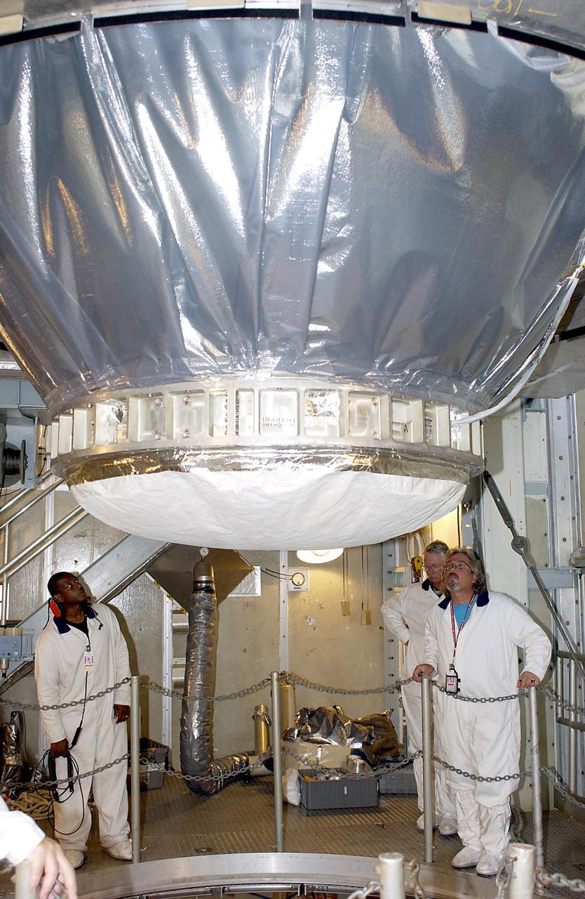 KENNEDY SPACE CENTER, FLA. -  On Launch Pad 17-A, Cape Canaveral Air Force Station,  workers watch as the Mars Exploration Rover 2 (MER-2), inside the transport canister, is lowered toward the Delta II rocket for mating.  MER-2 is one of NASA's twin Mars Exploration Rovers designed to study the history of water on Mars. These robotic geologists are equipped with a robotic arm, a drilling tool, three spectrometers, and four pairs of cameras that allow them to have a human-like, 3D view of the terrain. Each rover could travel as far as 100 meters in one day to act as Mars scientists' eyes and hands, exploring an environment where humans can't yet go.  MER-2 is scheduled to launch no earlier than June 8 as MER-A.