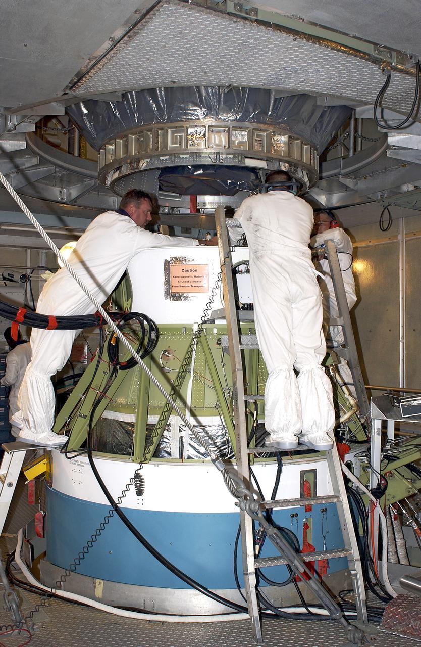 KENNEDY SPACE CENTER, FLA. - On Launch Pad 17-A, Cape Canaveral Air Force Station,  workers attach the Mars Exploration Rover 2 (MER-2) , above, to the second stage of the Delta II rocket, below.  MER-2 is one of NASA's twin Mars Exploration Rovers designed to study the history of water on Mars. These robotic geologists are equipped with a robotic arm, a drilling tool, three spectrometers, and four pairs of cameras that allow them to have a human-like, 3D view of the terrain. Each rover could travel as far as 100 meters in one day to act as Mars scientists' eyes and hands, exploring an environment where humans can't yet go.  MER-2 is scheduled to launch no earlier than June 8 as MER-A.