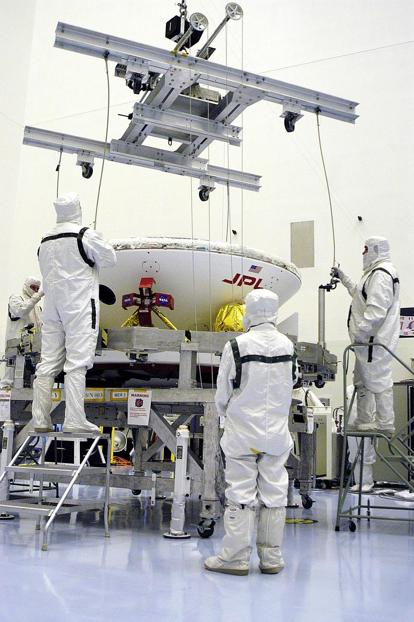 KENNEDY SPACE CENTER, FLA. - In the Payload Hazardous Servicing Facility, workers attach a crane to the Mars Exploration Rover-1 (MER-B) as they prepare to lift it onto a spin table during preflight processing of the spacecraft.  The rover is scheduled to launch aboard a Delta II rocket on June 25.  NASA’s twin Mars Exploration Rovers are designed to study the history of water on Mars. These robotic geologists are equipped with a robotic arm, a drilling tool, three spectrometers, and four pairs of cameras that allow them to have a human-like, 3D view of the terrain. Each rover could travel as far as 100 meters in one day to act as Mars scientists' eyes and hands, exploring an environment where humans are not yet able to go. The launch of MER-2 (MER-A) is tentatively set for June 8.