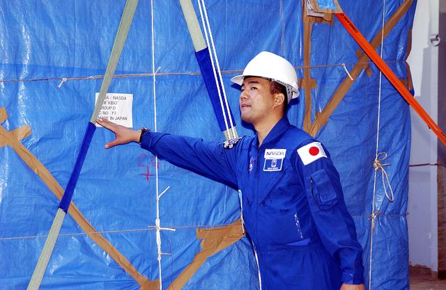 NASA image: KENNEDY SPACE CENTER, FLA. - Astronaut Soichi Noguchi, with the National Space Development Agency of Japan (NASDA), looks at the Japanese Experiment Module after its arrival at Port Canaveral, Fla.   Built by the Tsukuba Space Center near Tokyo, the pressurized module is the first element of the JEM, Japan’s primary contribution to the space station, to be delivered to KSC. It will enhance the unique research capabilities of the orbiting complex by providing an additional shirt-sleeve environment for astronauts to conduct science experiments. The JEM also includes two logistics modules, an exposed pallet for space environment experiments and a robotic manipulator system that are still under construction in Japan. The various JEM components will be assembled in space over the course of three space shuttle missions.
