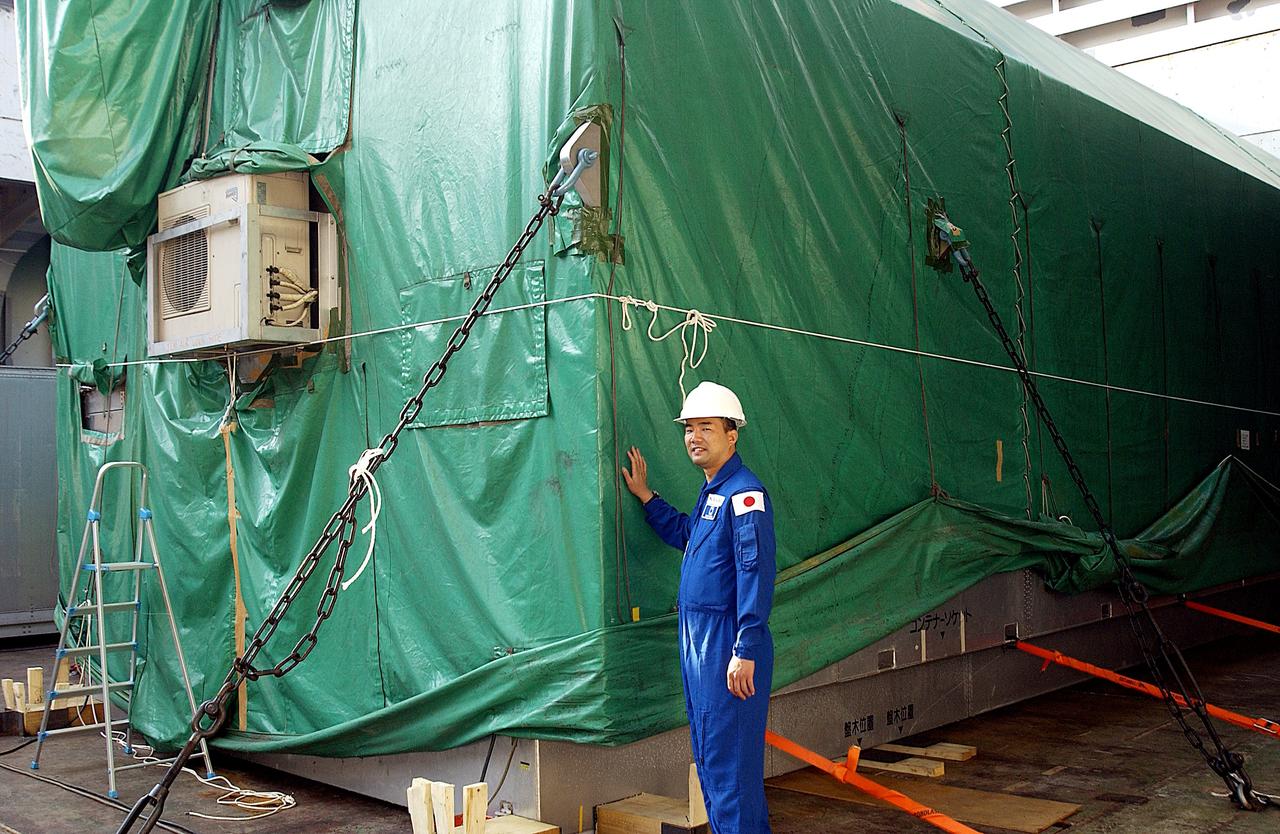 KENNEDY SPACE CENTER, FLA. - Astronaut Soichi Noguchi, with the National Space Development Agency of Japan (NASDA), stands next to the Japanese Experiment Module after its arrival at Port Canaveral, Fla.   Built by the Tsukuba Space Center near Tokyo, the pressurized module is the first element of the JEM, Japan’s primary contribution to the space station, to be delivered to KSC. It will enhance the unique research capabilities of the orbiting complex by providing an additional shirt-sleeve environment for astronauts to conduct science experiments. The JEM also includes two logistics modules, an exposed pallet for space environment experiments and a robotic manipulator system that are still under construction in Japan. The various JEM components will be assembled in space over the course of three space shuttle missions.