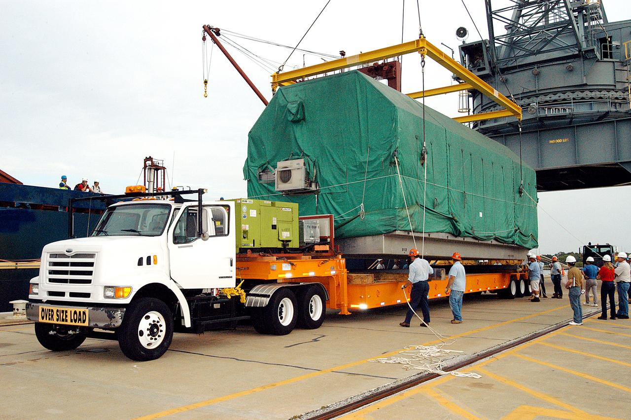 KENNEDY SPACE CENTER, FLA. - At Port Canaveral, workers release the overhead crane that lifted the Pressurized Module of the Japanese Experiment Module (JEM) from the ship onto the truck bed.  The container transport ship carrying JEM departed May 2 from Yokohama Harbor in Japan for the voyage to the United States. The National Space Development Agency of Japan (NASDA) developed the laboratory at the Tsukuba Space Center near Tokyo. The Pressurized Module is the first element of the JEM, named "Kibo" (Hope), to be delivered to KSC, and will be transferred to KSC’s Space Station Processing Facility.  The JEM is Japan's primary contribution to the Station. It will enhance the unique research capabilities of the orbiting complex by providing an additional environment for astronauts to conduct science experiments.  The JEM also includes an exposed facility (platform) for space environment experiments, a robotic manipulator system, and two logistics modules. The various JEM components will be  assembled in space over the course of three Shuttle missions.