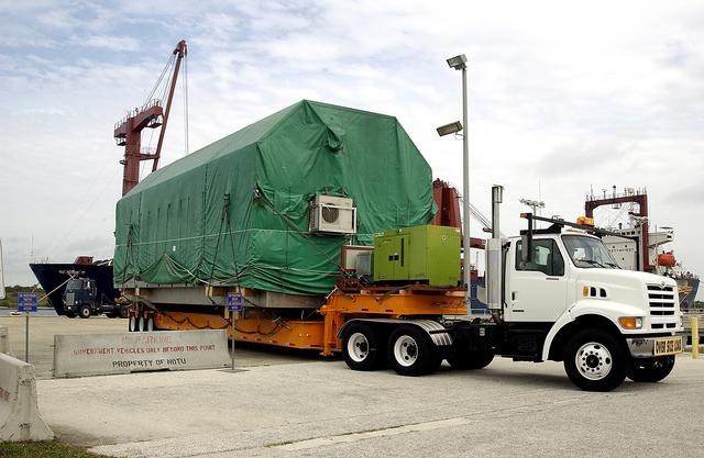 NASA image: KENNEDY SPACE CENTER, FLA. -  The transporter rolls out of Port Canaveral with the Pressurized Module of the Japanese Experiment Module (JEM) aboard.  The National Space Development Agency of Japan (NASDA) developed the laboratory at the Tsukuba Space Center near Tokyo. The Pressurized Module is the first element of the JEM, named "Kibo" (Hope), to be delivered to KSC, and will be transferred to KSC’s Space Station Processing Facility.  The JEM is Japan's primary contribution to the Station. It will enhance the unique research capabilities of the orbiting complex by providing an additional environment for astronauts to conduct science experiments.  The JEM also includes an exposed facility (platform) for space environment experiments, a robotic manipulator system, and two logistics modules. The various JEM components will be  assembled in space over the course of three Shuttle missions.