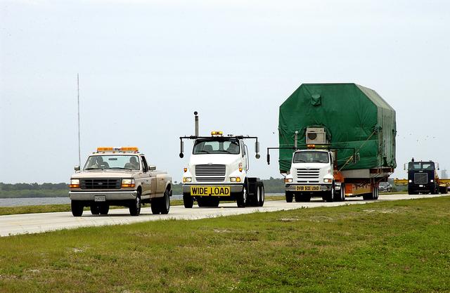 NASA image: KENNEDY SPACE CENTER, FLA. -  A convoy accompanies the truck transporting the Pressurized Module of the Japanese Experiment Module (JEM) to KSC’s Space Station Processing Facility.  The National Space Development Agency of Japan (NASDA) developed the laboratory at the Tsukuba Space Center near Tokyo. The Pressurized Module is the first element of the JEM, named "Kibo" (Hope), to be delivered to KSC.  The JEM is Japan's primary contribution to the Station. It will enhance the unique research capabilities of the orbiting complex by providing an additional environment for astronauts to conduct science experiments.  The JEM also includes an exposed facility (platform) for space environment experiments, a robotic manipulator system, and two logistics modules. The various JEM components will be  assembled in space over the course of three Shuttle missions.