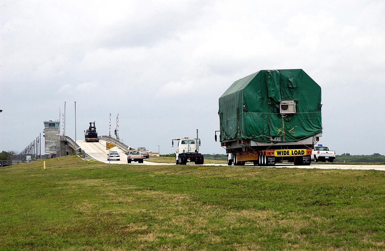 KENNEDY SPACE CENTER, FLA. - A convoy accompanies the truck transporting the Pressurized Module of the Japanese Experiment Module (JEM) to KSC’s Space Station Processing Facility.  The National Space Development Agency of Japan (NASDA) developed the laboratory at the Tsukuba Space Center near Tokyo. The Pressurized Module is the first element of the JEM, named "Kibo" (Hope), to be delivered to KSC.  The JEM is Japan's primary contribution to the Station. It will enhance the unique research capabilities of the orbiting complex by providing an additional environment for astronauts to conduct science experiments.  The JEM also includes an exposed facility (platform) for space environment experiments, a robotic manipulator system, and two logistics modules. The various JEM components will be  assembled in space over the course of three Shuttle missions.