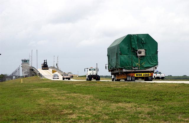 NASA image: KENNEDY SPACE CENTER, FLA. - A convoy accompanies the truck transporting the Pressurized Module of the Japanese Experiment Module (JEM) to KSC’s Space Station Processing Facility.  The National Space Development Agency of Japan (NASDA) developed the laboratory at the Tsukuba Space Center near Tokyo. The Pressurized Module is the first element of the JEM, named "Kibo" (Hope), to be delivered to KSC.  The JEM is Japan's primary contribution to the Station. It will enhance the unique research capabilities of the orbiting complex by providing an additional environment for astronauts to conduct science experiments.  The JEM also includes an exposed facility (platform) for space environment experiments, a robotic manipulator system, and two logistics modules. The various JEM components will be  assembled in space over the course of three Shuttle missions.