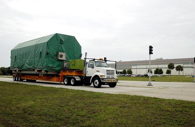 NASA image: KENNEDY SPACE CENTER, FLA. - The truck transporting the Pressurized Module of the Japanese Experiment Module (JEM) to KSC’s Space Station Processing Facility arrives on Center.  The National Space Development Agency of Japan (NASDA) developed the laboratory at the Tsukuba Space Center near Tokyo. The Pressurized Module is the first element of the JEM, named "Kibo" (Hope), to be delivered to KSC.  The JEM is Japan's primary contribution to the Station. It will enhance the unique research capabilities of the orbiting complex by providing an additional environment for astronauts to conduct science experiments.  The JEM also includes an exposed facility (platform) for space environment experiments, a robotic manipulator system, and two logistics modules. The various JEM components will be  assembled in space over the course of three Shuttle missions.