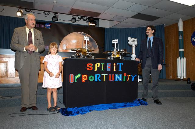 NASA image: KENNEDY SPACE CENTER, FLA. -  Nine-year-old Sofi Collis proudly presents the names she selected for the Mars Exploration Rovers  -- "Spirit" and "Opportunity" --  during a press conference.  Also participating in the press conference are NASA Administrator Sean O'Keefe (left) and Brad Justus, LEGO Co. senior vice president (right).  The names Sofi suggested were selected from more than 10,000 student entries in an essay contest managed for NASA by the LEGO Company.   NASA's twin Mars Exploration Rovers are designed to study the history of water on Mars. These robotic geologists are equipped with a robotic arm, a drilling tool, three spectrometers, and four pairs of cameras that allow them to have a human-like, 3D view of the terrain. Each rover could travel as far as 100 meters in one day to act as Mars scientists' eyes and hands, exploring an environment where humans are not yet able to go. MER-A, with the rover Spirit aboard, is scheduled to launch on June 8 at 2:06 p.m. EDT, with two launch opportunities each day during a launch period that closes on June 24.