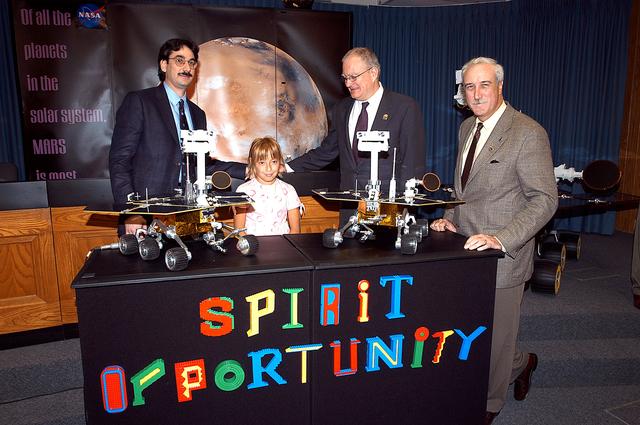 NASA image: KENNEDY SPACE CENTER, FLA. -  Nine-year-old Sofi Collis poses proudly with a banner displaying the names she selected for the Mars Exploration Rovers -- "Spirit" and "Opportunity" -- during a press conference. Participating in the press conference are, from left, Brad Justus, LEGO Co. senior vice president; Sofi Collis, a third grade student from Arizona; Dr. John Marburger, science advisor to the President and director of the Office of Science and Technology Policy; and NASA Administrator Sean O'Keefe. The names Sofi suggested were selected from more than 10,000 student entries in an essay contest managed for NASA by the LEGO Company. NASA's twin Mars Exploration Rovers are designed to study the history of water on Mars. These robotic geologists are equipped with a robotic arm, a drilling tool, three spectrometers, and four pairs of cameras that allow them to have a human-like, 3D view of the terrain. Each rover could travel as far as 100 meters in one day to act as Mars scientists' eyes and hands, exploring an environment where humans are not yet able to go. MER-A, with the rover Spirit aboard, is scheduled to launch on June 8 at 2:06 p.m. EDT, with two launch opportunities each day during a launch period that closes on June 24.