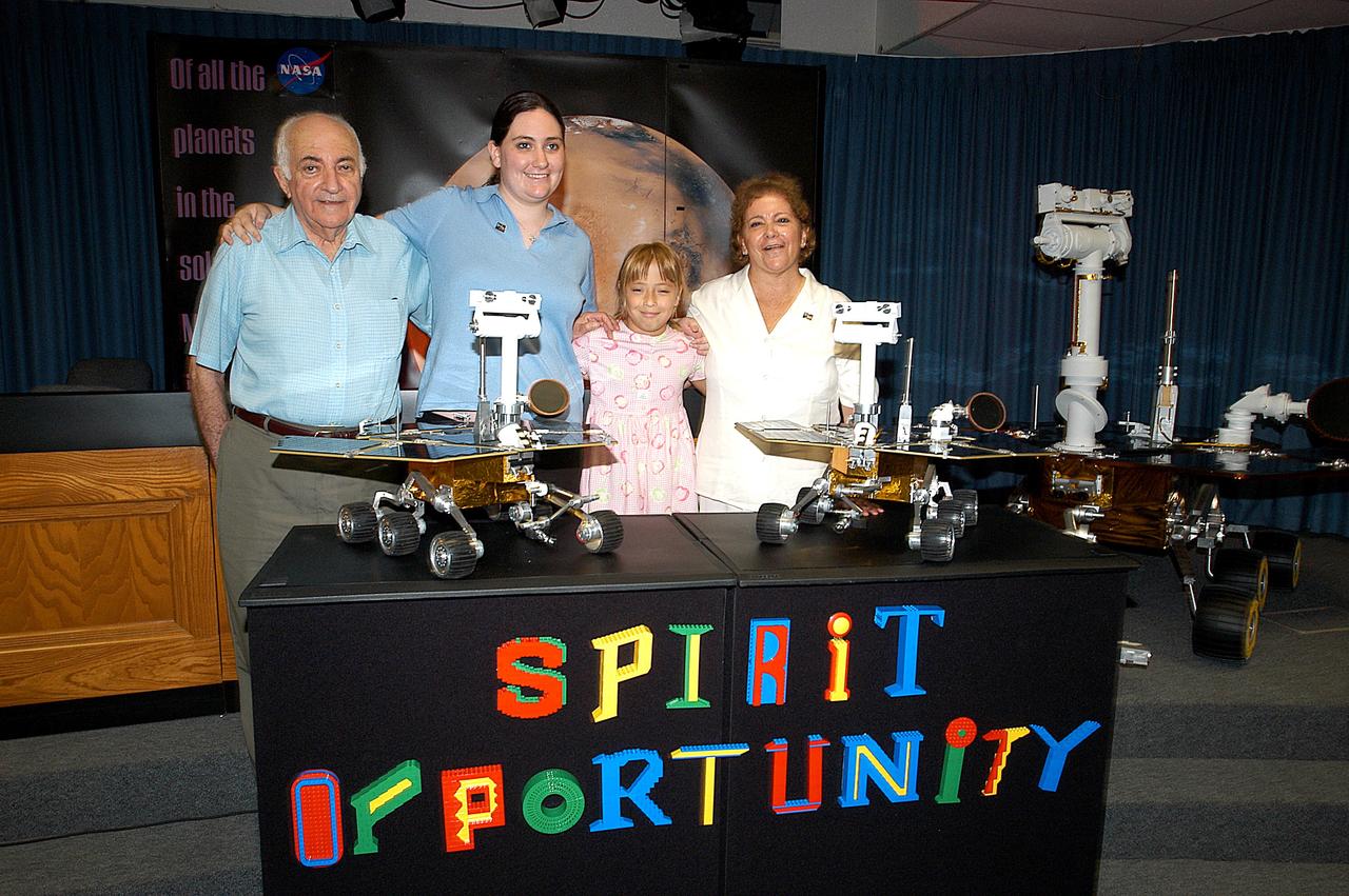 KENNEDY SPACE CENTER, FLA. -  Nine-year-old Sofi Collis (third from left) and her family pose proudly with a banner displaying the names she selected for the Mars Exploration Rovers -- "Spirit" and "Opportunity" -- following a press conference announcing the names. The names Sofi suggested were chosen from more than 10,000 student entries in an essay contest managed for NASA by the LEGO Company. NASA's twin Mars Exploration Rovers are designed to study the history of water on Mars. These robotic geologists are equipped with a robotic arm, a drilling tool, three spectrometers, and four pairs of cameras that allow them to have a human-like, 3D view of the terrain. Each rover could travel as far as 100 meters in one day to act as Mars scientists' eyes and hands, exploring an environment where humans are not yet able to go. MER-A, with the rover Spirit aboard, is scheduled to launch on June 8 at 2:06 p.m. EDT, with two launch opportunities each day during a launch period that closes on June 24.