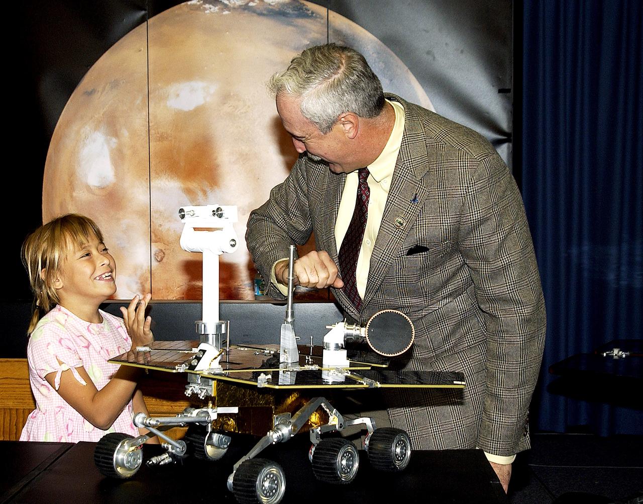 KENNEDY SPACE CENTER, FLA. -  Nine-year-old Sofi Collis (left) shares a light moment with NASA Administrator Sean O'Keefe at a press conference.   The Siberian-born Arizona resident wrote the winning entry in the Name the Rovers Contest sponsored by NASA and the Lego Co., a Denmark-based toymaker, with collaboration from the Planetary Society, Pasadena, Calif.  The names she selected for the Mars Exploration Rovers are "Spirit" and "Opportunity." The third grader's essay was chosen from more than 10,000 American student entries.  NASA's twin Mars Exploration Rovers are designed to study the history of water on Mars. These robotic geologists are equipped with a robotic arm, a drilling tool, three spectrometers, and four pairs of cameras that allow them to have a human-like, 3D view of the terrain. Each rover could travel as far as 100 meters in one day to act as Mars scientists' eyes and hands, exploring an environment where humans are not yet able to go. MER-A, with the rover Spirit aboard, is scheduled to launch on June 8 at 2:06 p.m. EDT, with two launch opportunities each day during a launch period that closes on June 24.