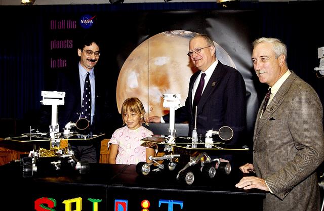 NASA image: KENNEDY SPACE CENTER, FLA. -  Nine-year-old Sofi Collis poses proudly with a banner displaying the names she selected for the Mars Exploration Rovers -- "Spirit" and "Opportunity" -- during a press conference. Participating in the press conference are, from left, Brad Justus, LEGO Co. senior vice president; Sofi Collis, third grade student from Arizona; Dr. John Marburger, science advisor to the President and director of the Office of Science and Technology Policy; and NASA Administrator Sean O'Keefe. The names Sofi suggested were selected from more than 10,000 student entries in an essay contest managed for NASA by the LEGO Company. NASA's twin Mars Exploration Rovers are designed to study the history of water on Mars. These robotic geologists are equipped with a robotic arm, a drilling tool, three spectrometers, and four pairs of cameras that allow them to have a human-like, 3D view of the terrain. Each rover could travel as far as 100 meters in one day to act as Mars scientists' eyes and hands, exploring an environment where humans are not yet able to go. MER-A, with the rover Spirit aboard, is scheduled to launch on June 8 at 2:06 p.m. EDT, with two launch opportunities each day during a launch period that closes on June 24.