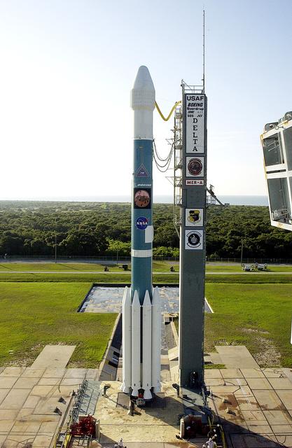 NASA image: KENNEDY SPACE CENTER, FLA. -    On Launch Complex 17-A, Cape Canaveral Air Force Station, the Boeing Delta II rocket and its Mars Exploration Rover (MER-A) payload are in the clear after tower rollback in preparation for a second attempt at launch.  The first attempt on June 8, 2003, was scrubbed due to bad weather in the vicinity.  MER-A is the first of two rovers being launched to Mars.  When the two rovers arrive at Mars in 2004, they will bounce to airbag-cushioned landings at sites offering a balance of favorable conditions for safe landings and interesting science. The rovers see sharper images, can explore farther and examine rocks better than anything that has ever landed on Mars.  The designated site for MER-A mission is Gusev Crater, which appears to have been a crater lake.  The second rover, MER-B, is scheduled to launch June 25.