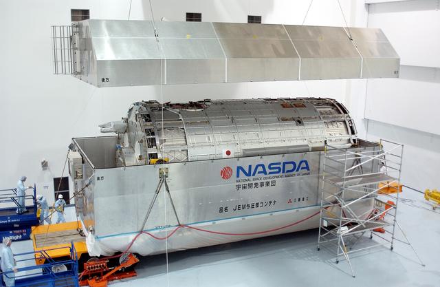 NASA image: KENNEDY SPACE CENTER, FLA. -  In the Space Station Processing Facility, the lid is removed from the container with the Japanese Experiment Module (JEM) pressure module inside.  A research laboratory, the pressurized module is the first element of the JEM, named "Kibo" (Hope), to be delivered to KSC.   The National Space Development Agency of Japan (NASDA) developed the laboratory at the Tsukuba Space Center near Tokyo and is Japan's primary contribution to the Station. It will enhance the unique research capabilities of the orbiting complex by providing an additional environment for astronauts to conduct science experiments.  The JEM also includes an exposed facility (platform) for space environment experiments, a robotic manipulator system, and two logistics modules. The various JEM components will be  assembled in space over the course of three Shuttle missions.