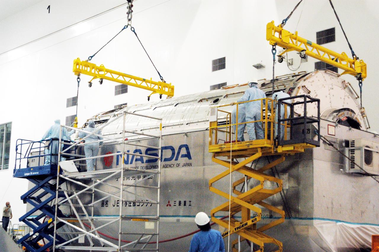 KENNEDY SPACE CENTER, FLA. -  Workers in the Space Station Processing Facility attach an overhead crane to the Japanese Experiment Module (JEM) pressure module inside its canister.  The module will be removed and transferred to a work stand in the Space Station Processing Facility.  A research laboratory, the pressurized module is the first element of the JEM, named "Kibo" (Hope), to be delivered to KSC.   The National Space Development Agency of Japan (NASDA) developed the laboratory at the Tsukuba Space Center near Tokyo and is Japan's primary contribution to the Station. It will enhance the unique research capabilities of the orbiting complex by providing an additional environment for astronauts to conduct science experiments.  The JEM also includes an exposed facility (platform) for space environment experiments, a robotic manipulator system, and two logistics modules. The various JEM components will be  assembled in space over the course of three Shuttle missions.